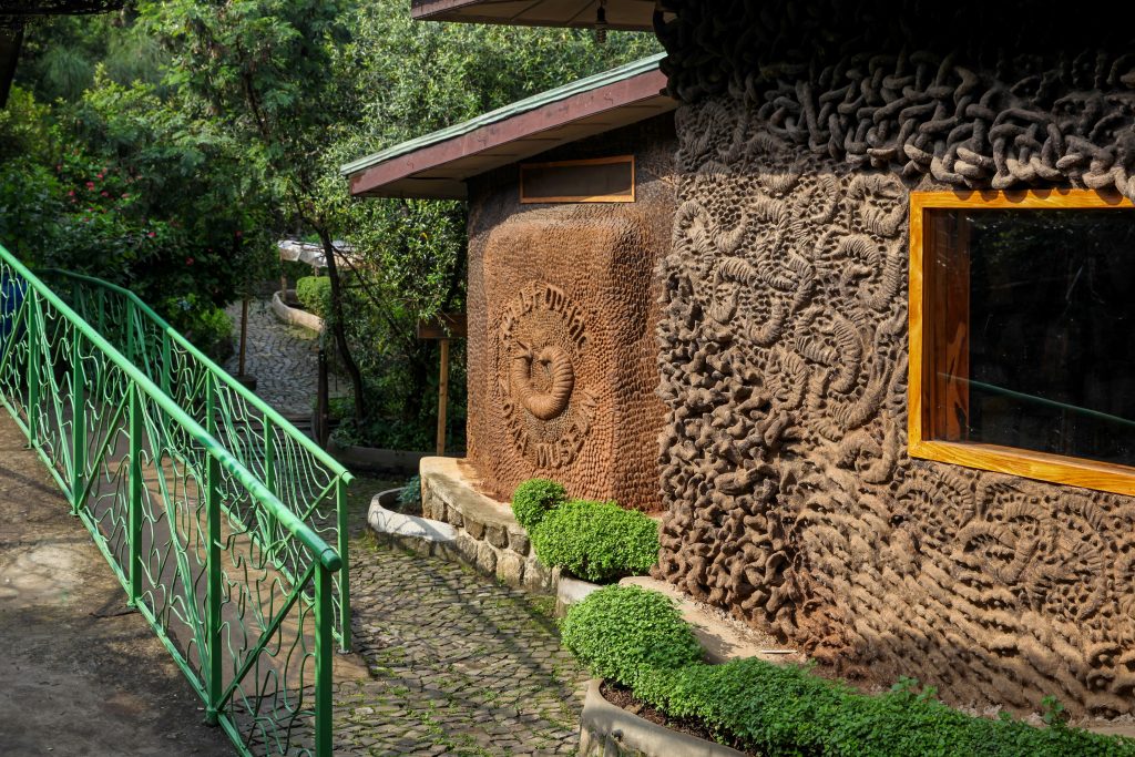 A colour photograph of the Zoma Museum building. It is clad in patterned clay and has a sign that says Zoma Museum in Amharic and English.